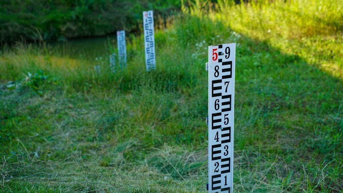 Outdoor water level measurement in a grassy field with clear signage for accurate readings.