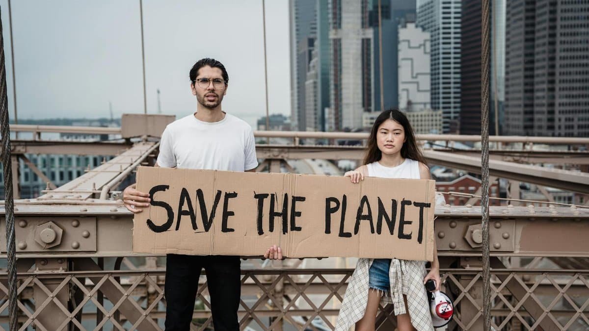 Two activists holding 'Save The Planet' sign at city protest.