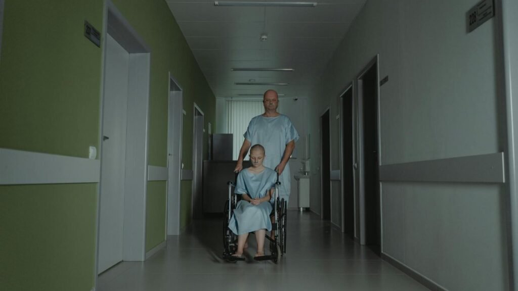 Two patients in hospital gowns navigate a hallway, symbolizing struggle and resilience.