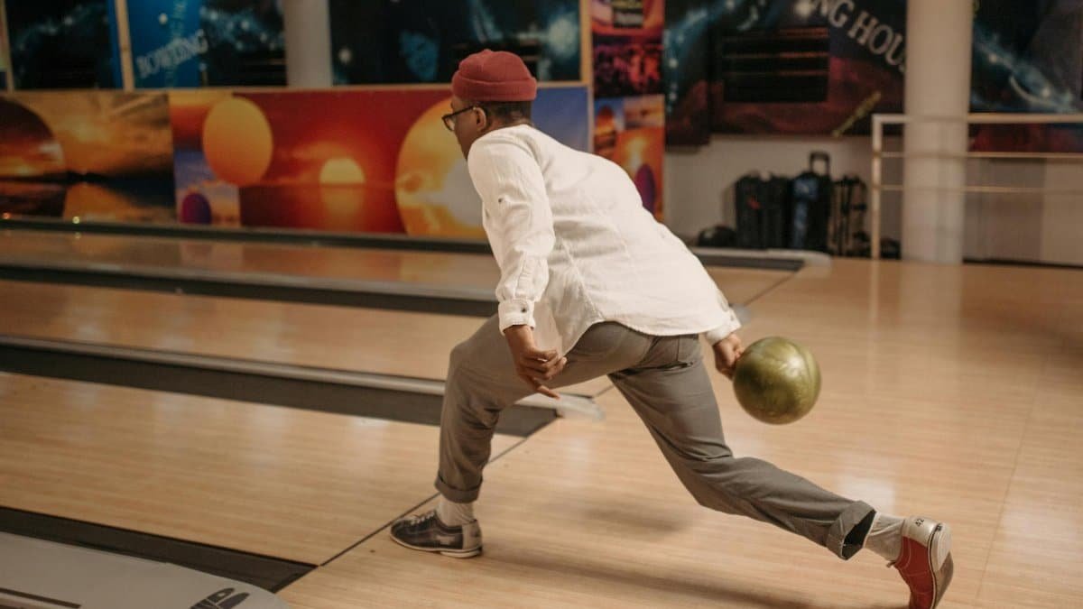 Focused man releasing a bowling ball at a modern indoor bowling alley.
