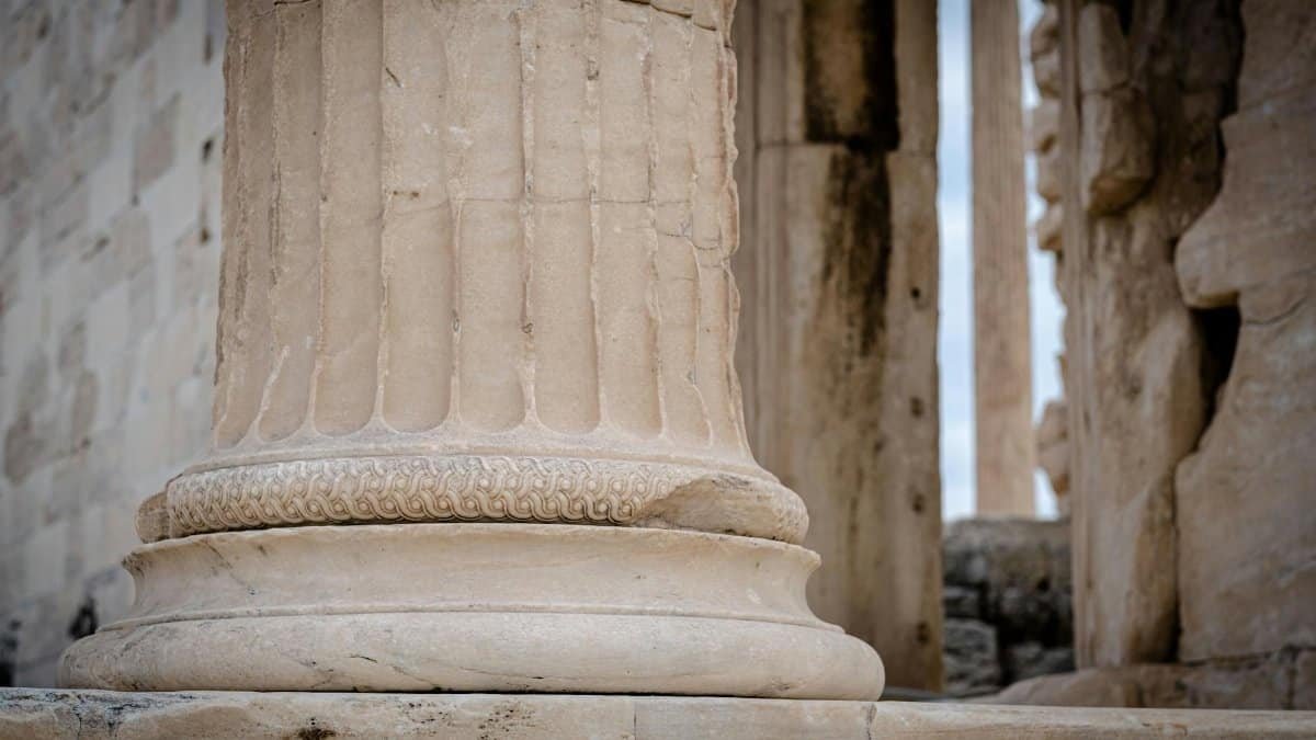 Close-up of an ancient stone column with intricate carvings in a classical structure.