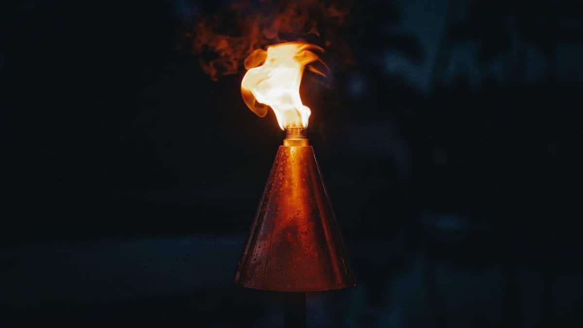 A dramatic close-up of a burning torch at night with a glowing flame.