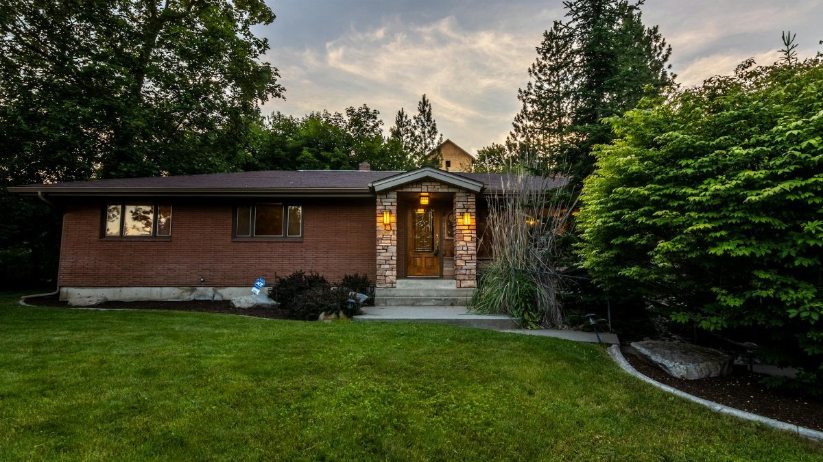 A cozy brick house surrounded by greenery, captured during twilight. Perfect for real estate promos.