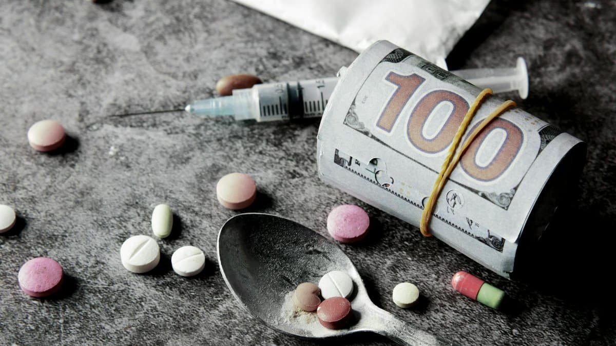 Symbolic representation of drug addiction and financial cost with pills and money.
