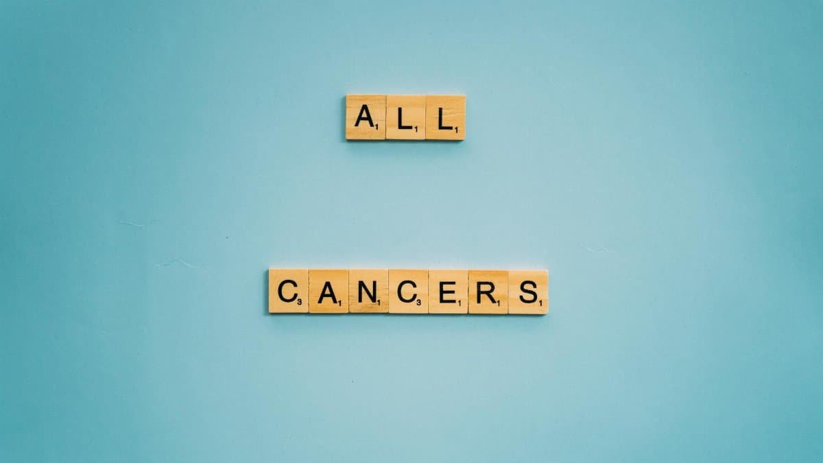Scrabble tiles forming 'All Cancers' on a light blue background, symbolizing cancer awareness.