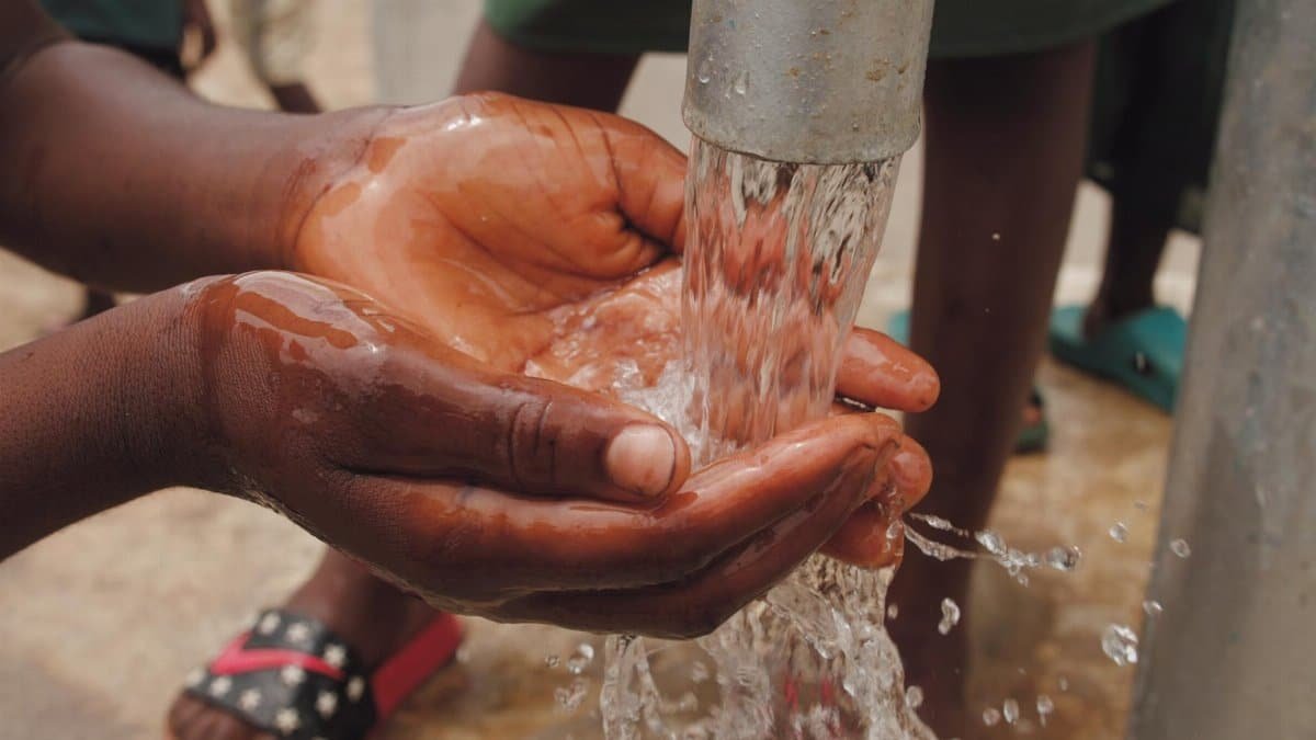 Hands capturing fresh water from a pump, highlighting cleanliness and resources.