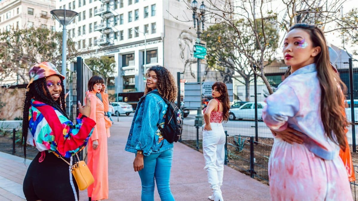 Diverse group of adults in colorful fashion posing on an urban street.
