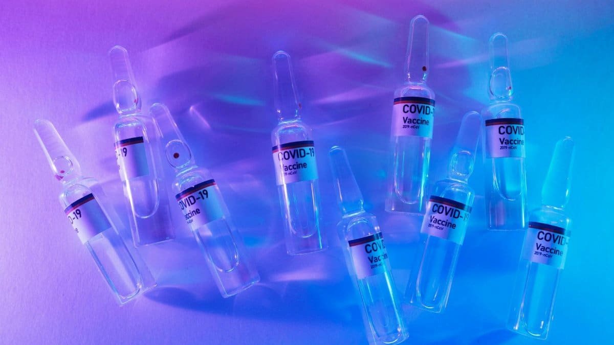 From above set of COVID 19 vaccines placed on table in modern laboratory with bright neon lights