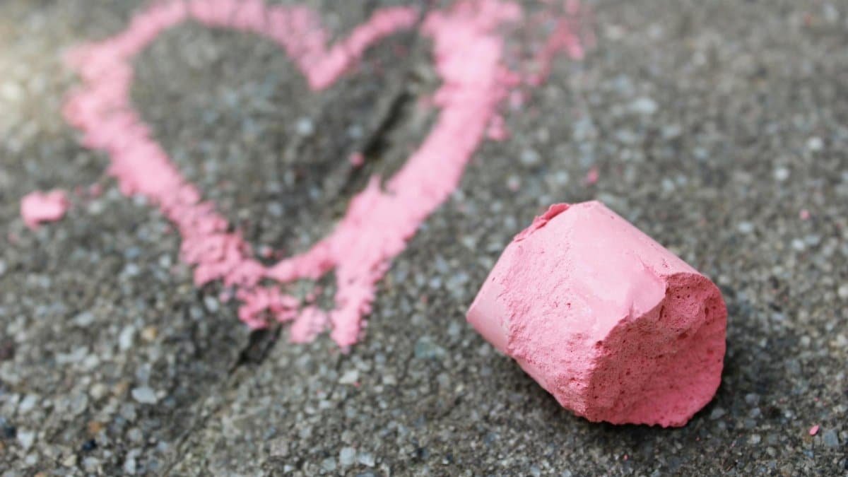 Close-up of a pink chalk heart on pavement, symbolizing love in Paris, France.