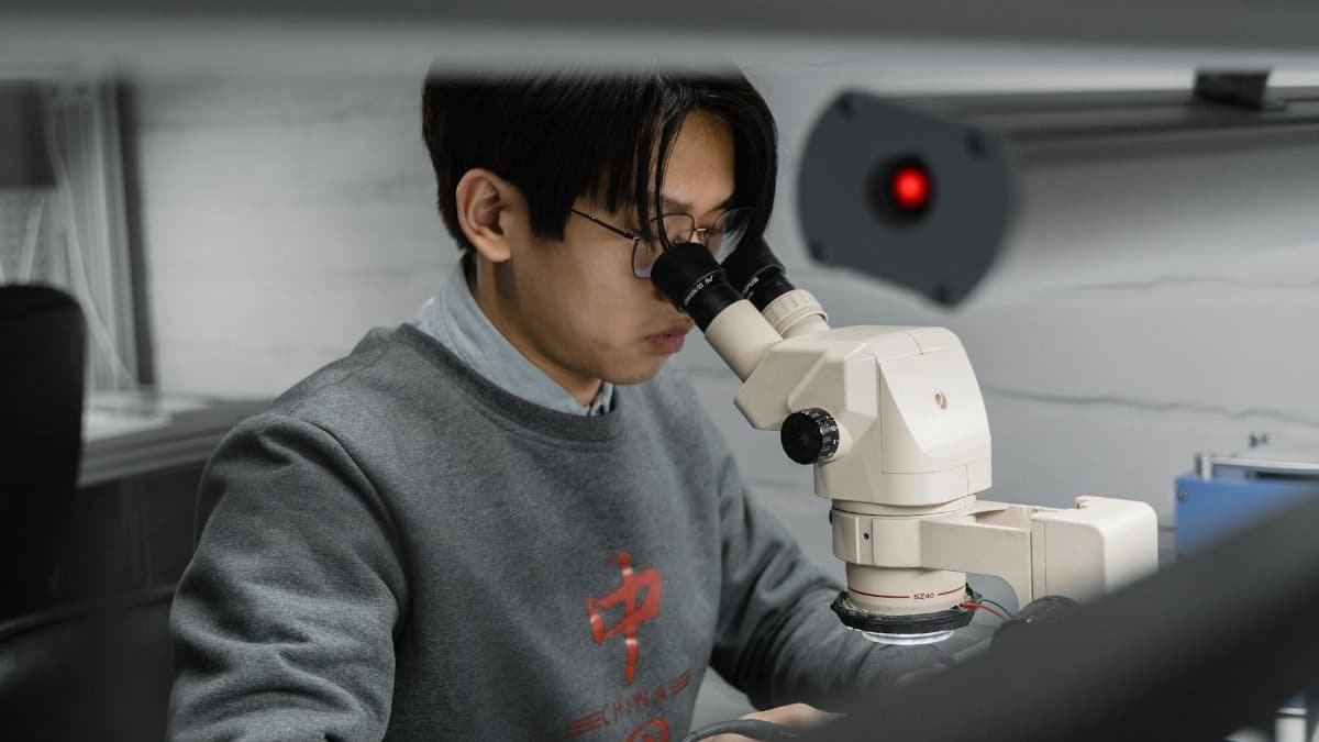 A man using a microscope for scientific research in a laboratory setting.