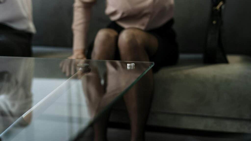 A wedding ring on a glass table symbolizes divorce and relationship issues.