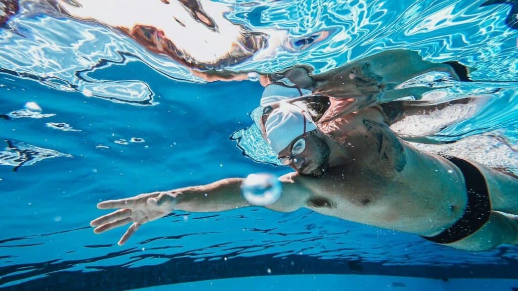 Swimmer practicing strokes underwater in a clear swimming pool, showcasing athletic technique.