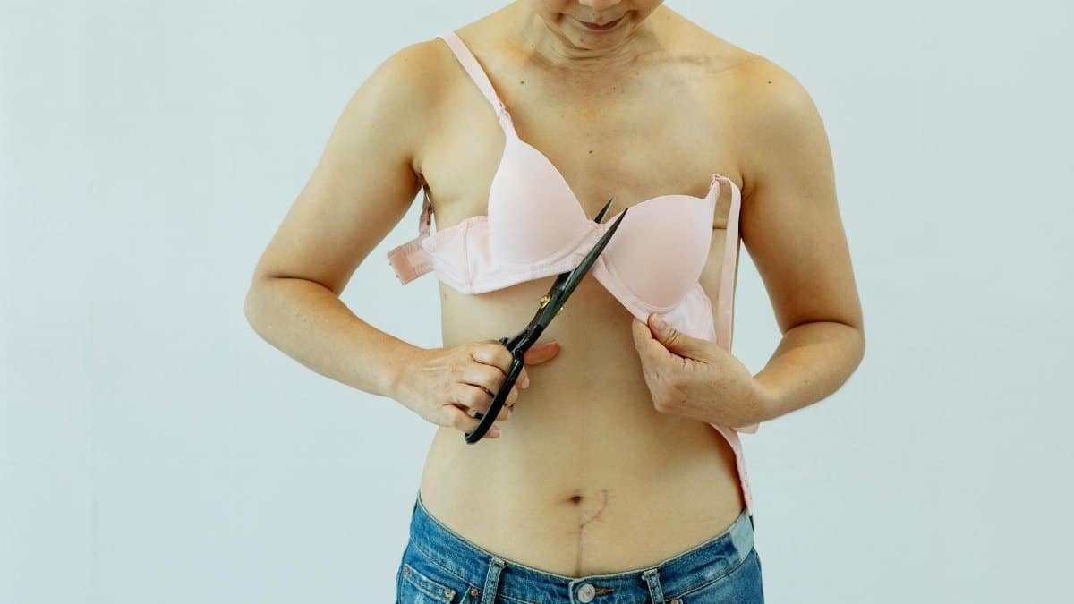 Cancer survivor cutting bra to symbolize empowerment and healing post-surgery.