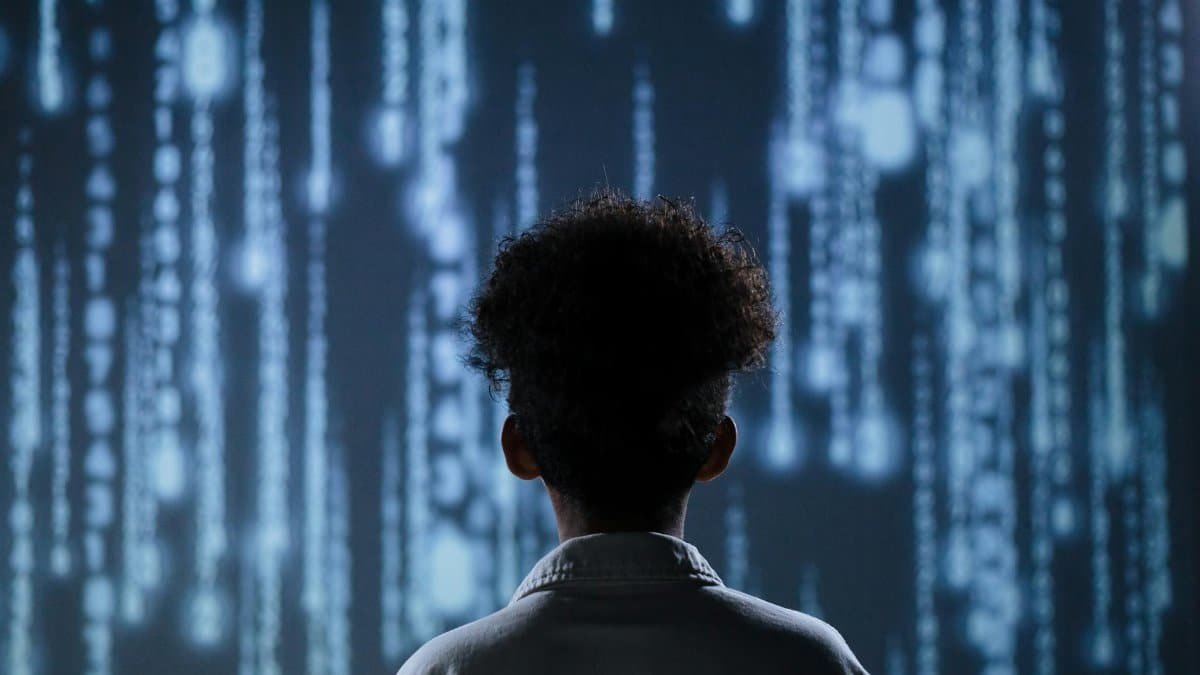 A young boy viewing a digital screen with data streams, symbolizing technology interaction.