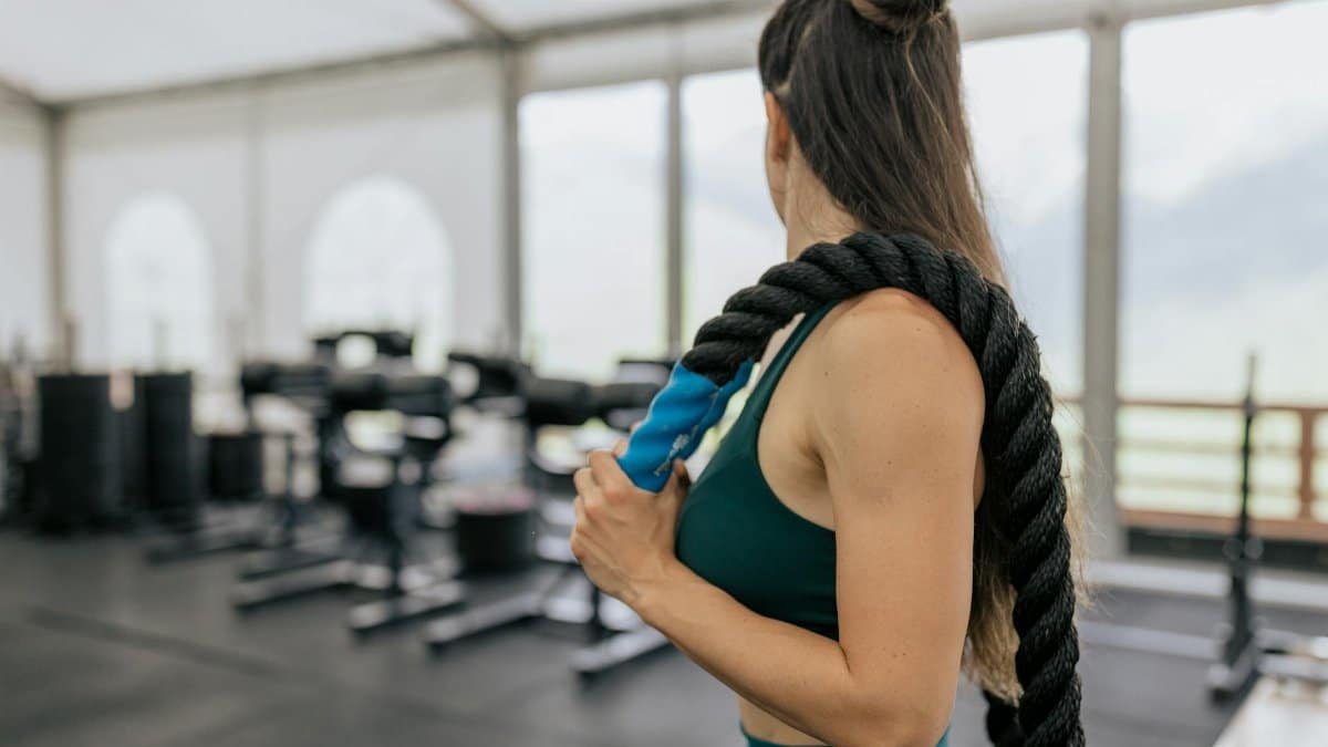 Woman in gym holding a battle rope, showcasing strength and fitness.