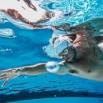 Swimmer practicing strokes underwater in a clear swimming pool, showcasing athletic technique.