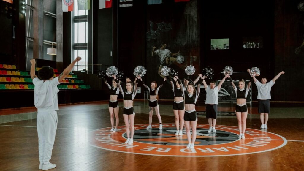 Cheerleaders practicing indoors with a coach, showing dynamic energy and teamwork.