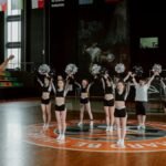 Cheerleaders practicing indoors with a coach, showing dynamic energy and teamwork.