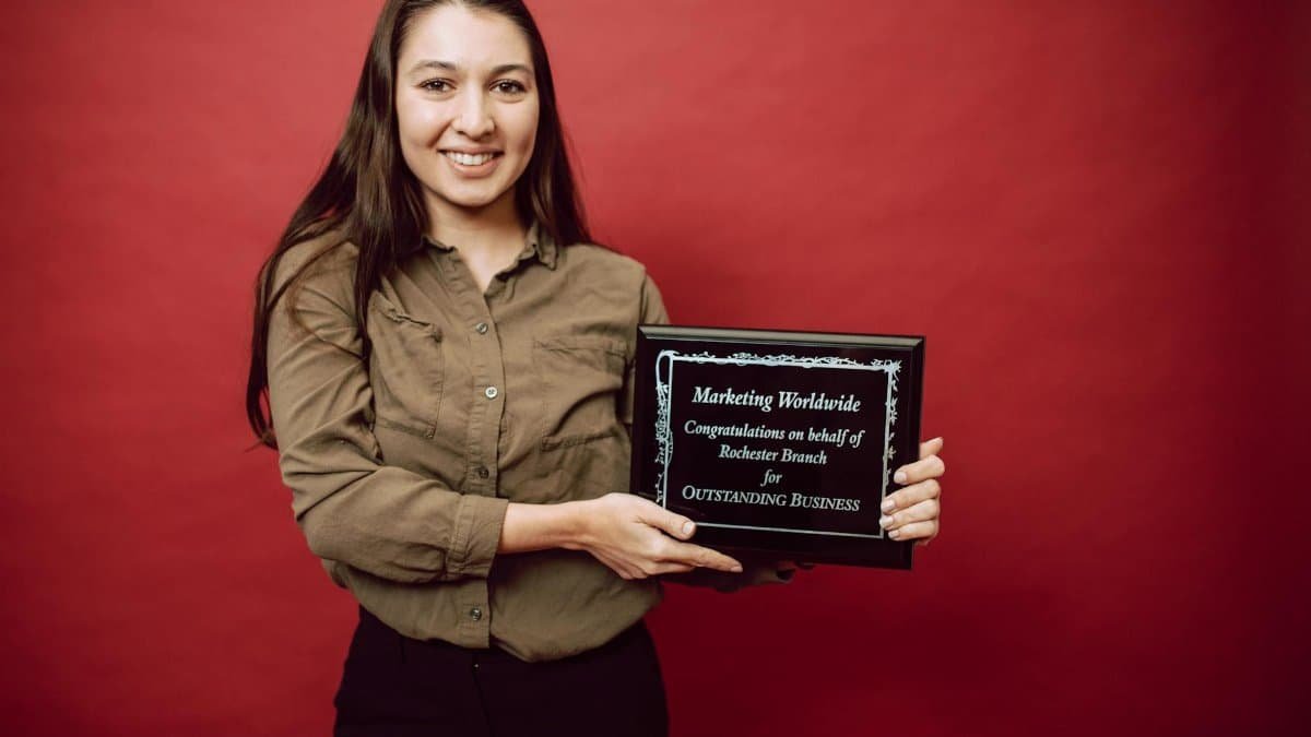 Smiling woman holding an award plaque for outstanding business. Achievement in leadership.
