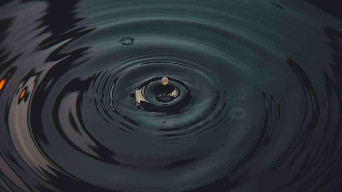 A mesmerizing splash of a water droplet creating ripples on a dark surface.