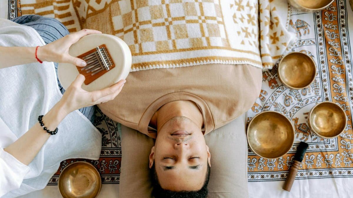 A serene sound bath session featuring a man relaxing with a kalimba and singing bowls.