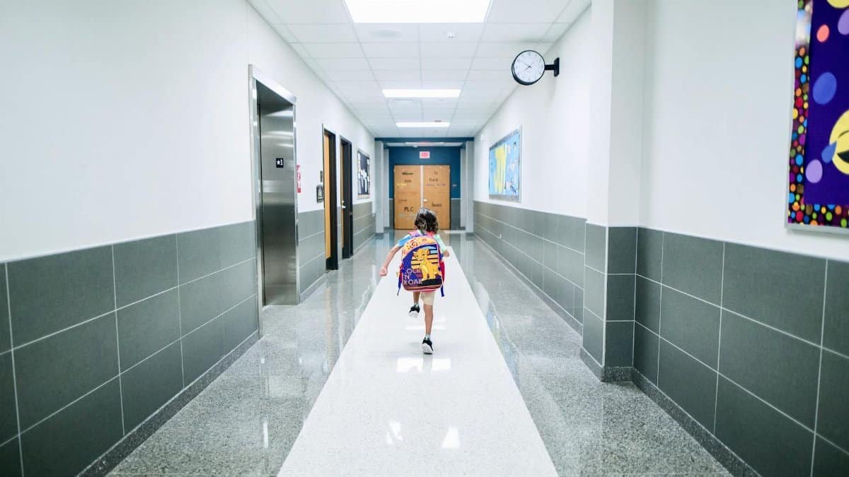 A child runs through a bright school hallway, emphasizing modern architecture and energy.