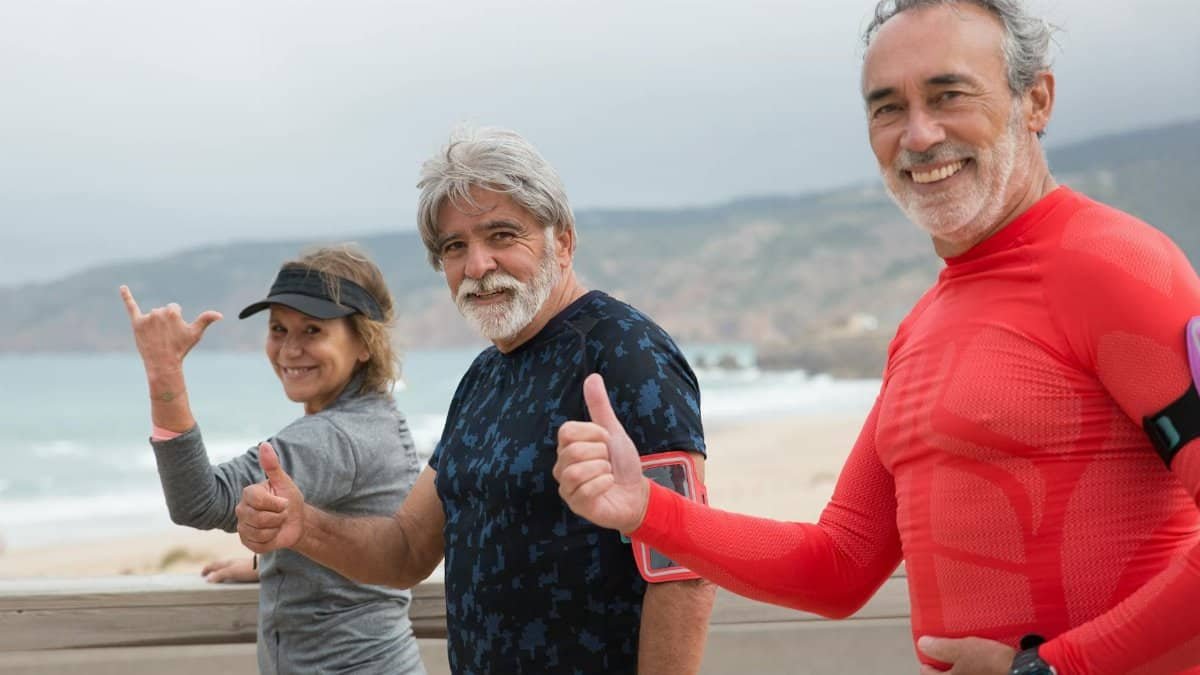 Smiling senior friends exercising on a beach in Portugal, embracing a healthy lifestyle.