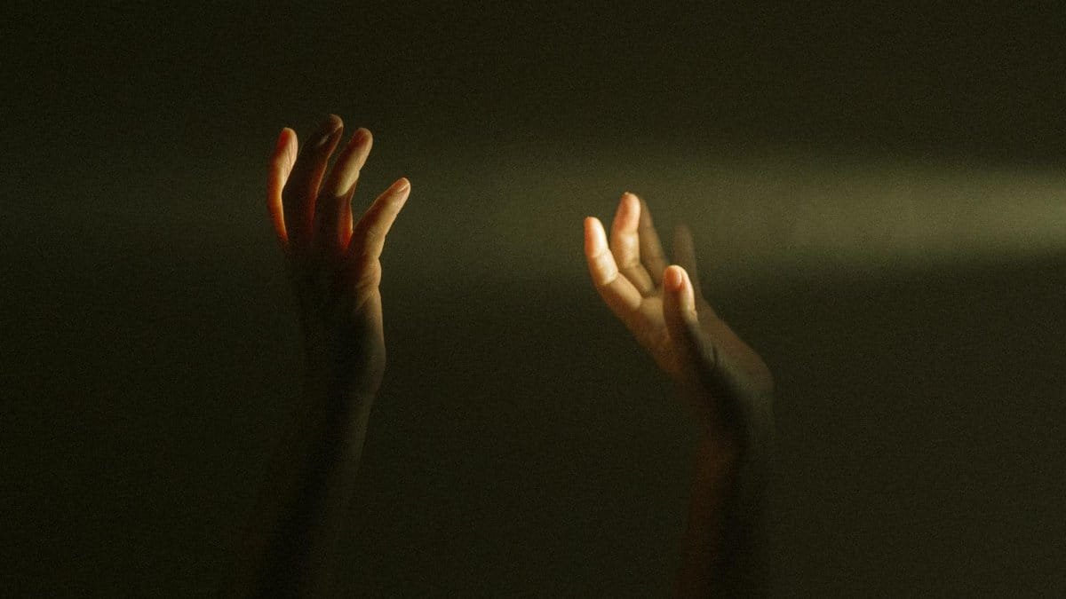 Expressive hands reaching towards a ray of light symbolize hope and mental resilience.