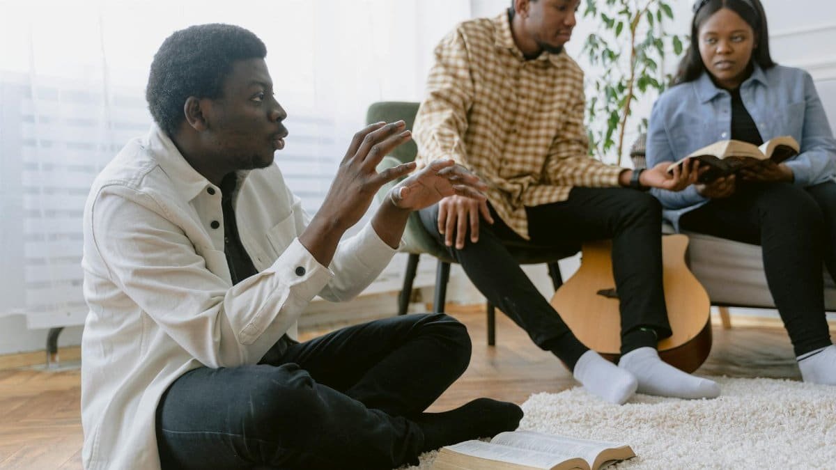 Three people engaged in a bible study discussion together inside a cozy room.