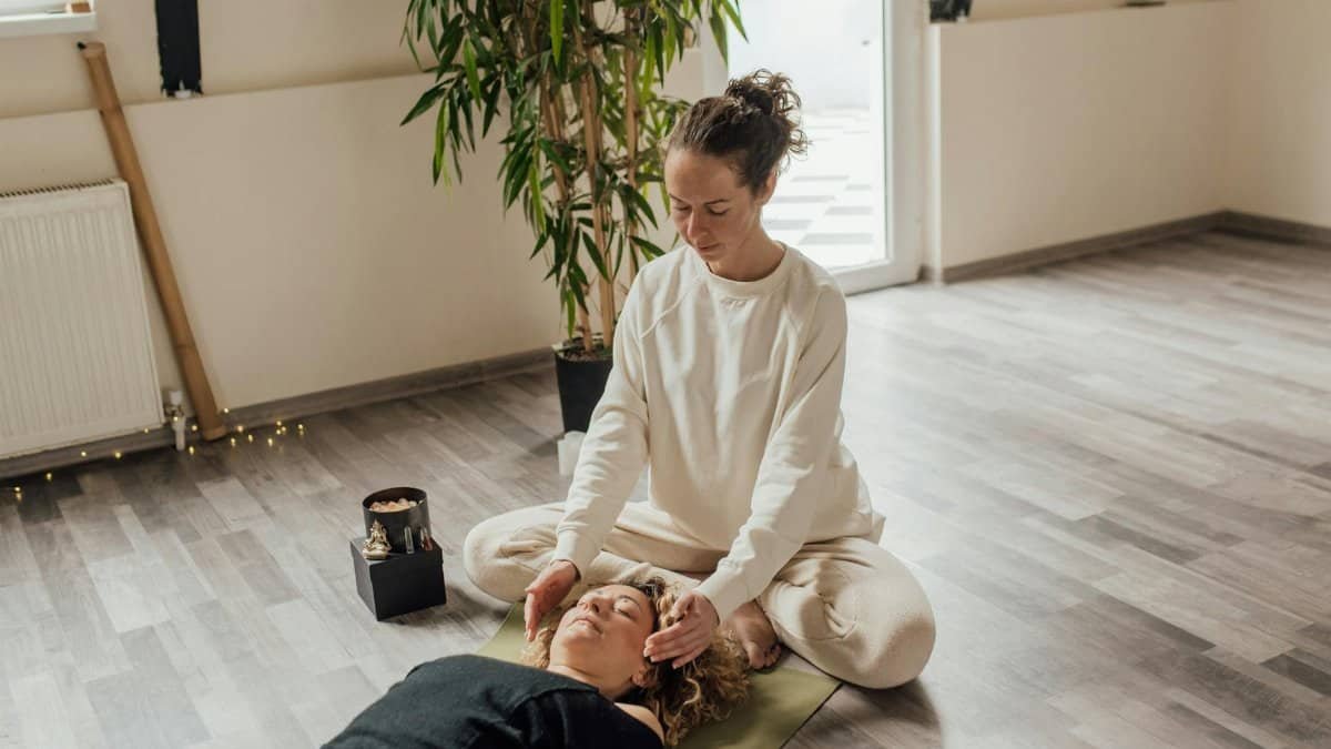 A calming Reiki session indoors with a therapist and patient on a yoga mat, focusing on healing energy.