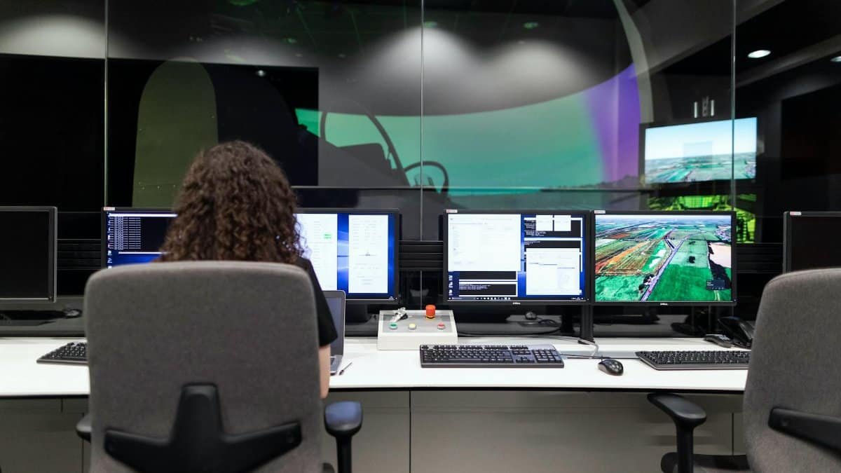 Female engineer managing multiple screens during a technology simulation in a control room.
