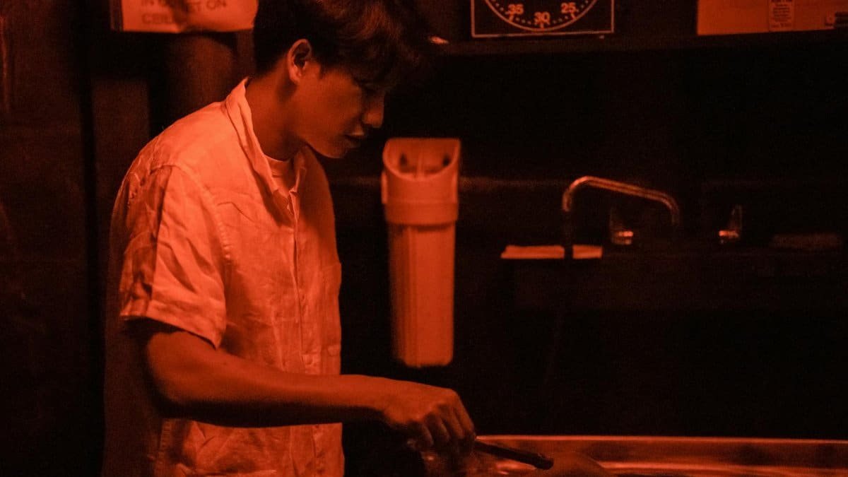A photographer processes images in a dimly lit darkroom, utilizing traditional techniques.