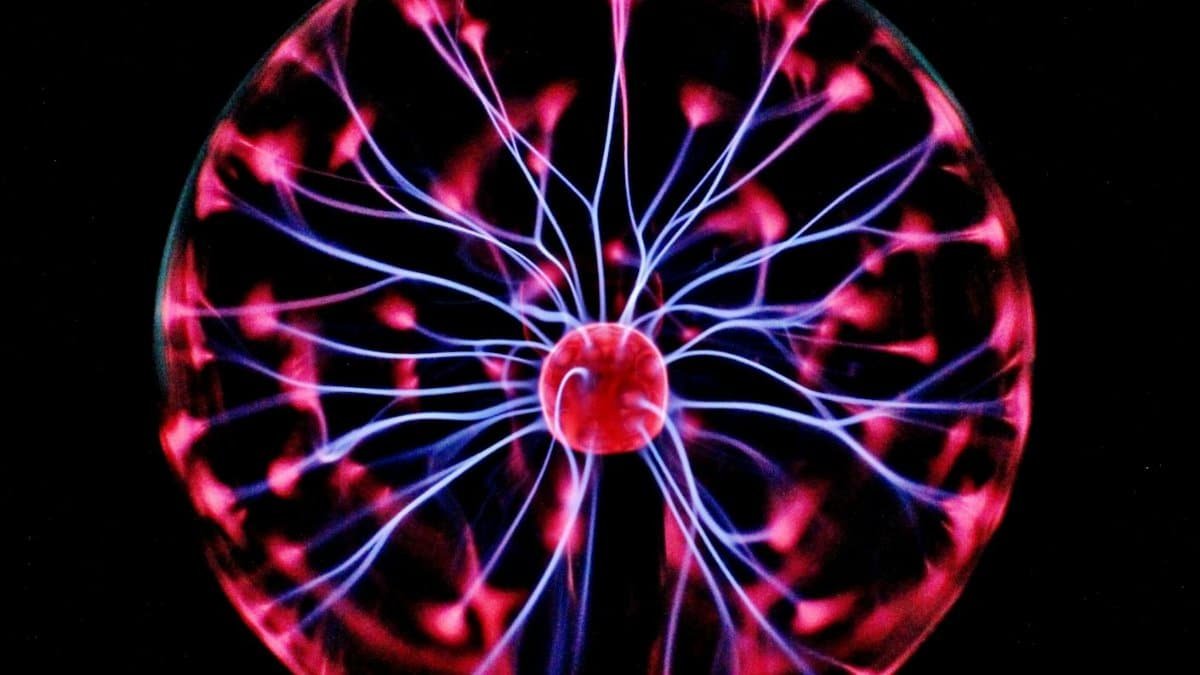 Close-up of a plasma globe with vibrant neon sparks against a dark background.