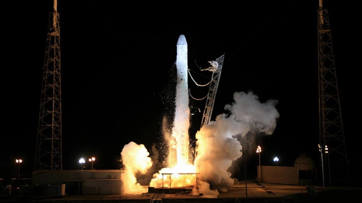 Modern solid rocket taking off into dark night sky during launching from spaceport