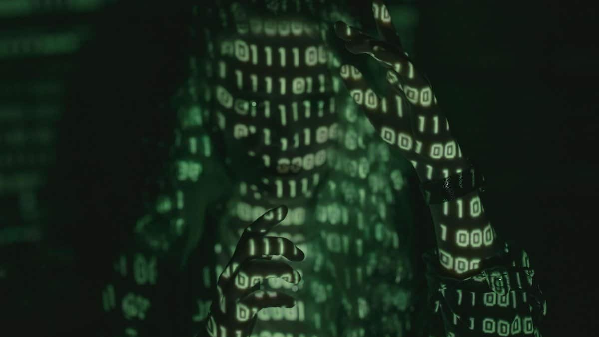 An unrecognizable person with binary code projected, symbolizing cybersecurity and digital coding.