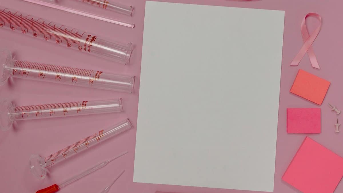 Flat lay of pink laboratory and office supplies promoting breast cancer awareness.