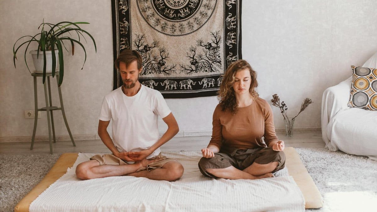 A serene atmosphere with two adults meditating indoors on a mat, embracing mindfulness.