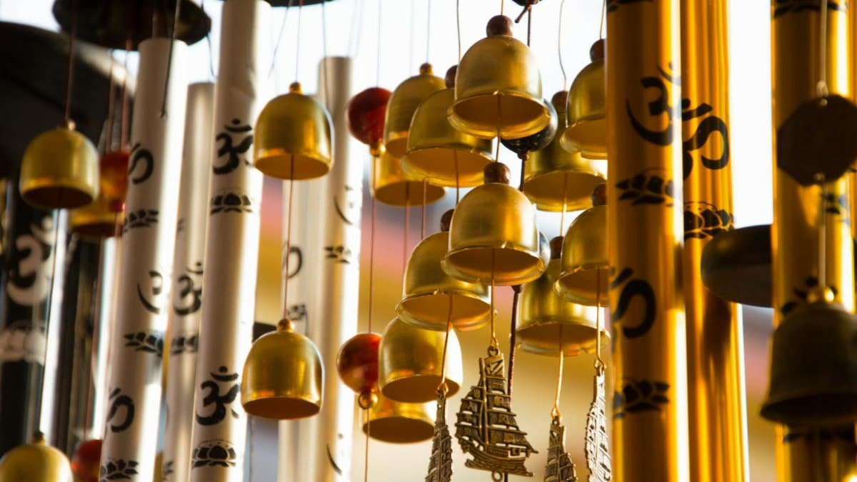 Close-up of intricately designed golden wind chimes featuring Om symbols, creating a serene ambiance.