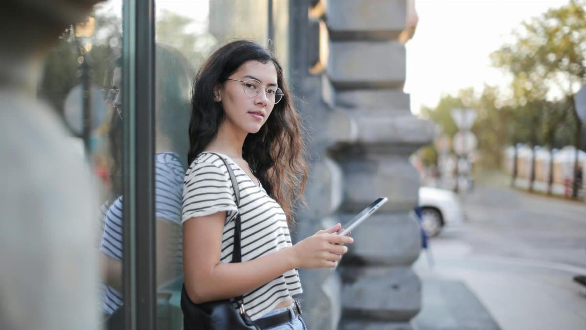A young woman enjoying leisure time outdoors, browsing on her tablet in a trendy urban setting.