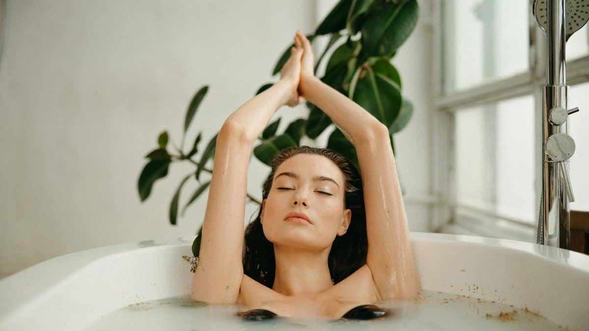 Serene woman in a bathtub, practicing self-care and relaxation amid tranquil surroundings.