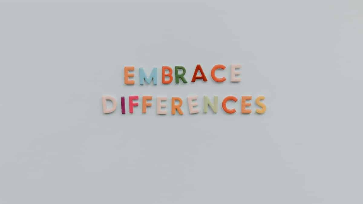Colorful letters spelling 'Embrace Differences' on a minimalist gray background highlighting inclusivity and diversity.