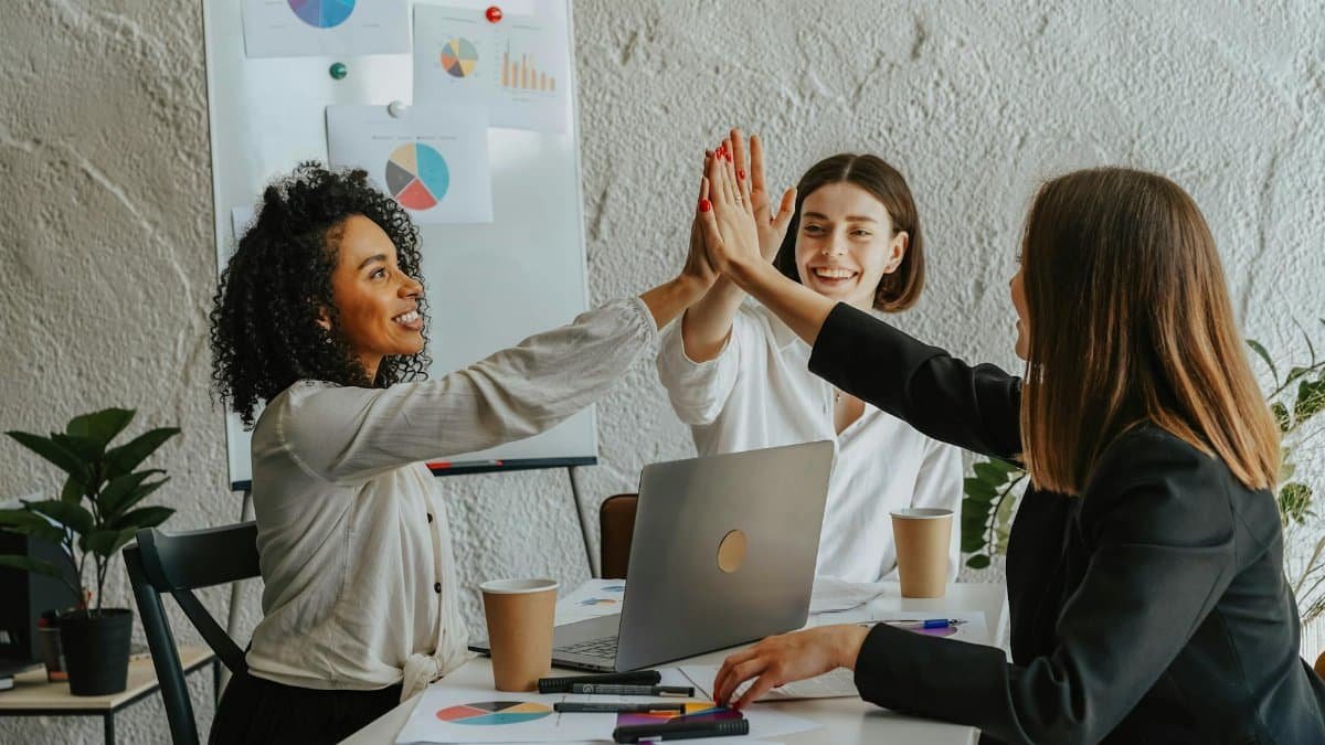 Three businesswomen in office having a high-five during a successful meeting.