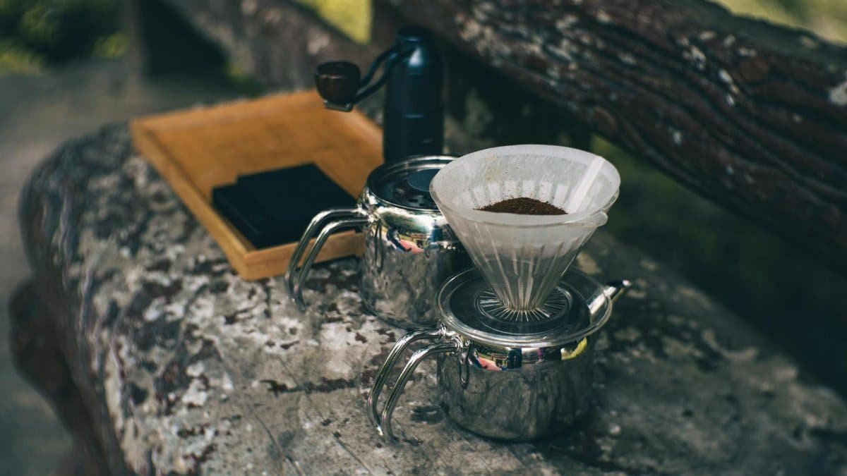 Rustic coffee brewing setup on a park bench, creating a warm and inviting outdoor experience.