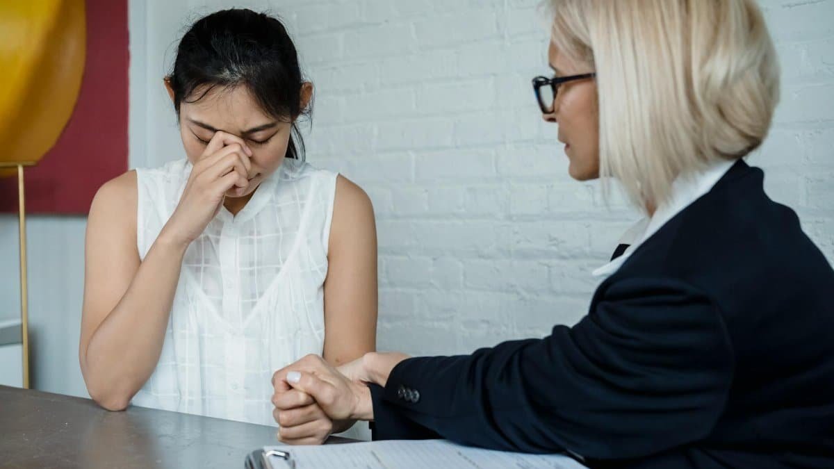 Emotional therapy session featuring a supportive female therapist helping a worried young woman.