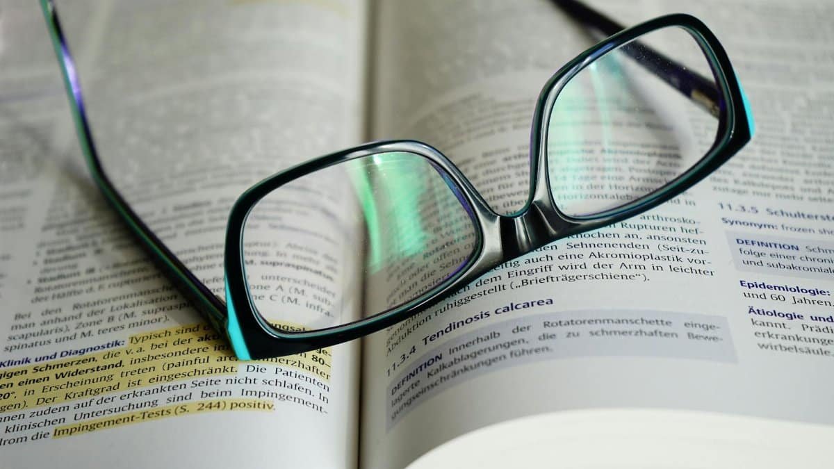 Reading glasses resting on an open book, symbolizing knowledge and learning.