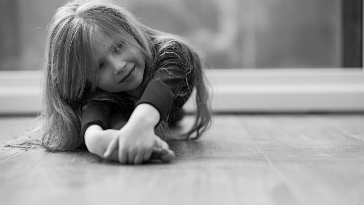 Charming black and white portrait of a young girl smiling indoors, showcasing innocence and joy.