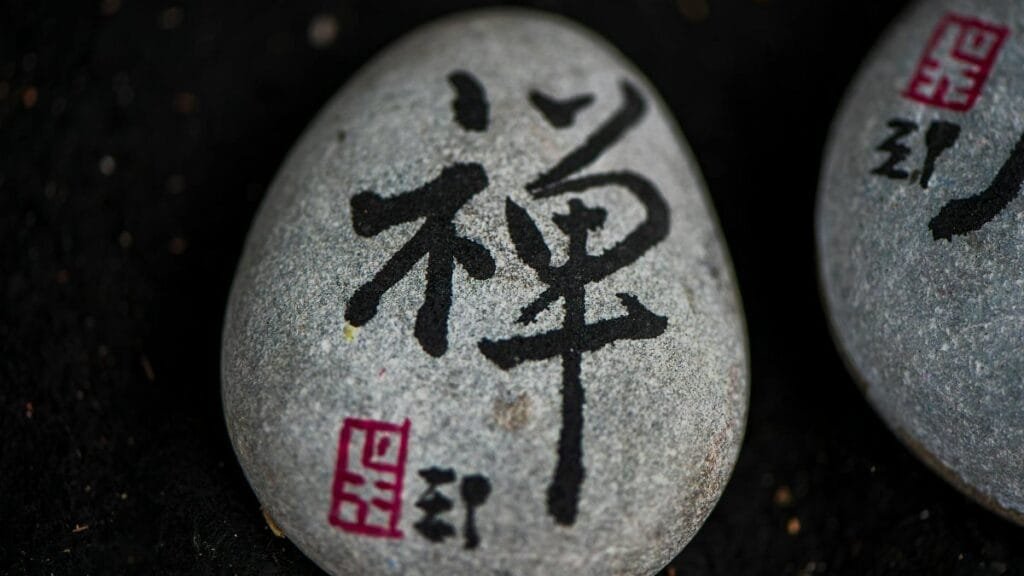 Close-up of a stone with Japanese calligraphy symbolizing zen and tranquility.