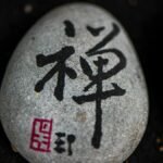 Close-up of a stone with Japanese calligraphy symbolizing zen and tranquility.