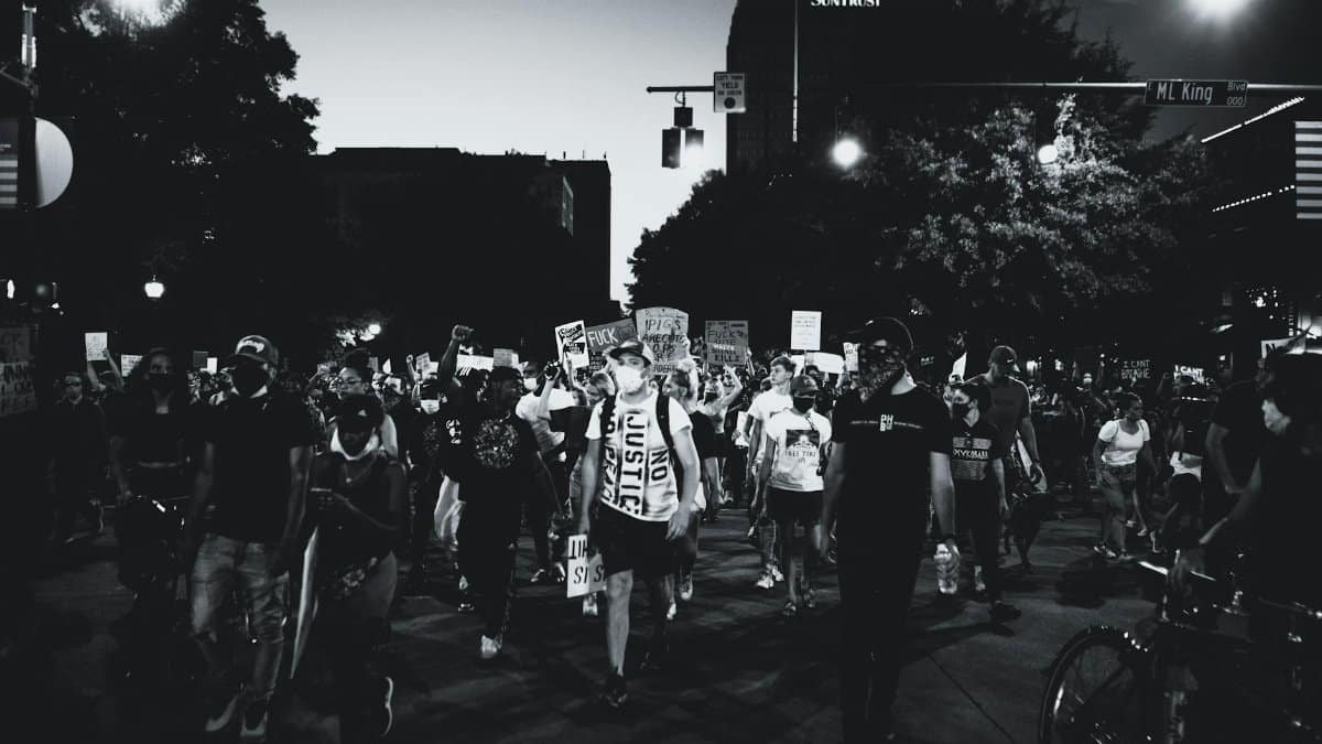 Black and white photo of a large protest march on city streets at night.