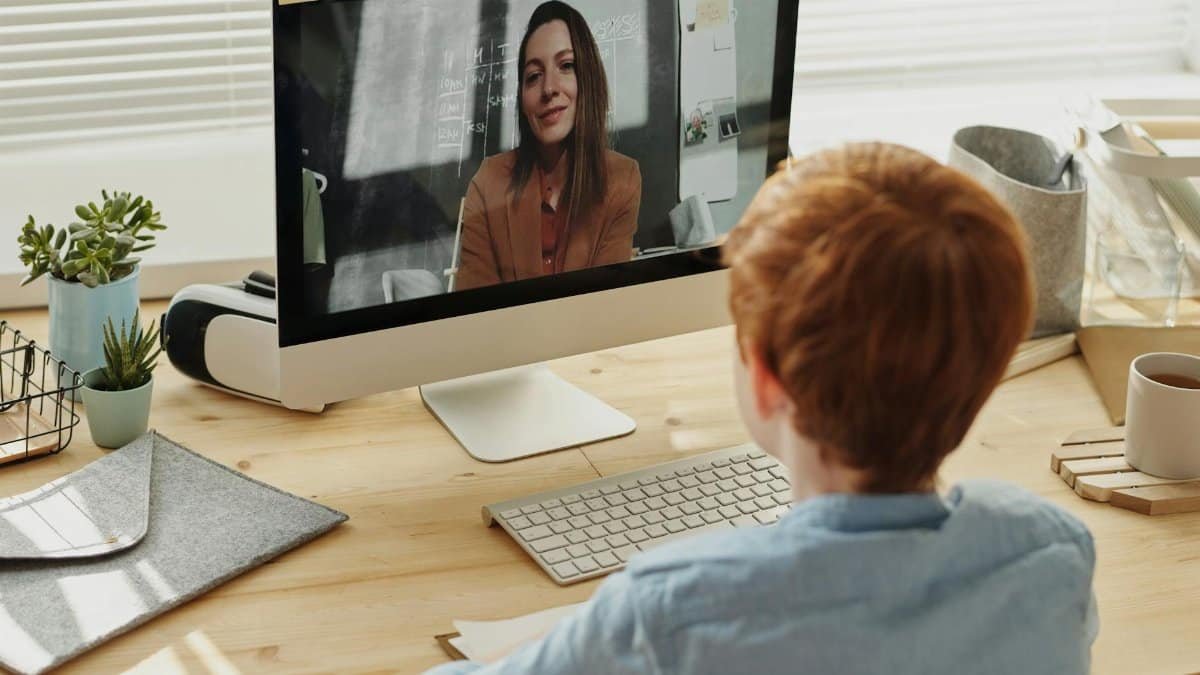 A child participating in an online class at home, focused on the educational content displayed on a desktop computer.